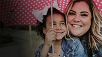 Woman and child smiling under an umbrella 